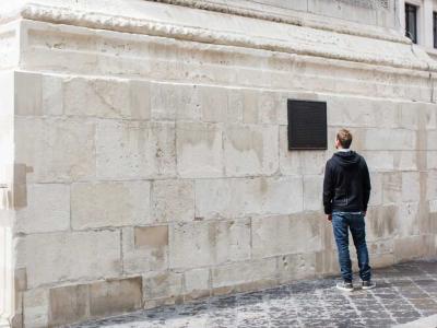 Man reading a plaque on the side of The Monument